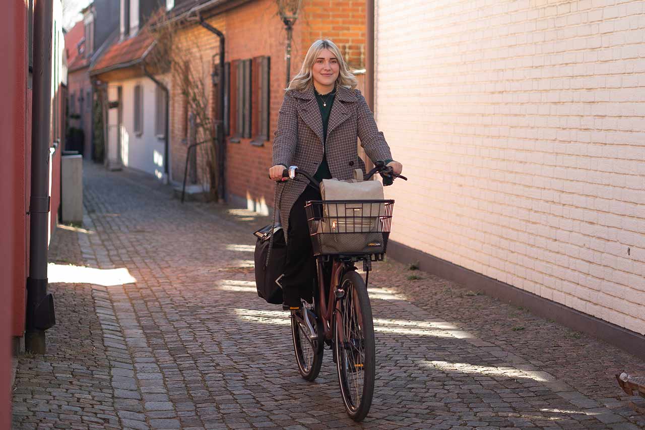Girl biking through town with a basket in the front