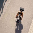 A sporty woman photographed from high above, cycling on a bike with chrome-colored details.