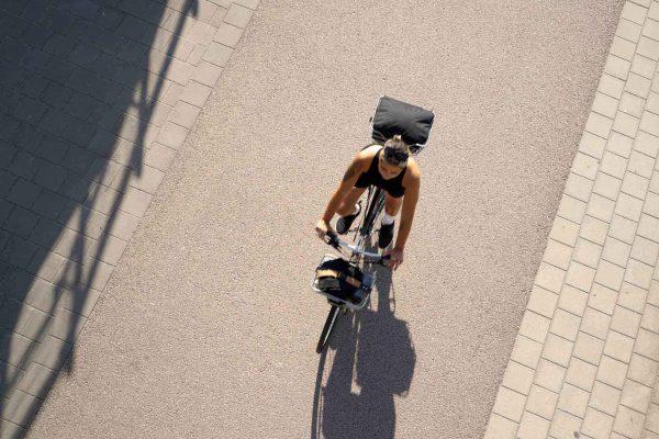 A sporty woman photographed from high above, cycling on a bike with chrome-colored details.