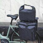 A closeup at a bicycle from the side, it has two sidepanniers and a topbag all in grey.