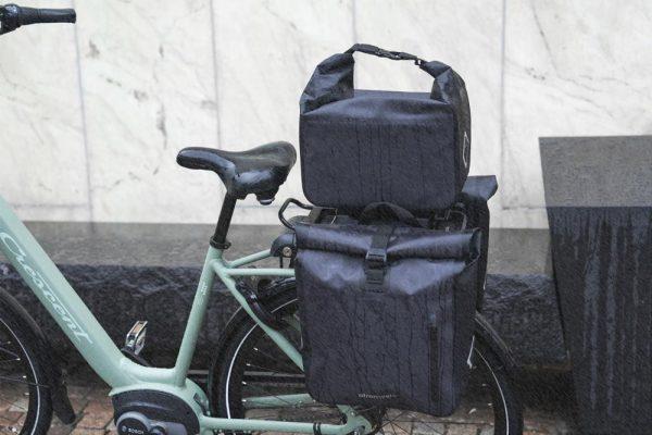 A closeup at a bicycle from the side, it has two sidepanniers and a topbag all in grey.