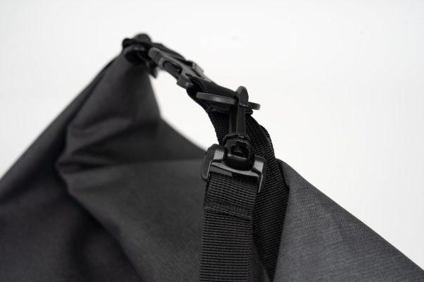 Closeup on handles and buckles on a grey bag with light grey background in studio