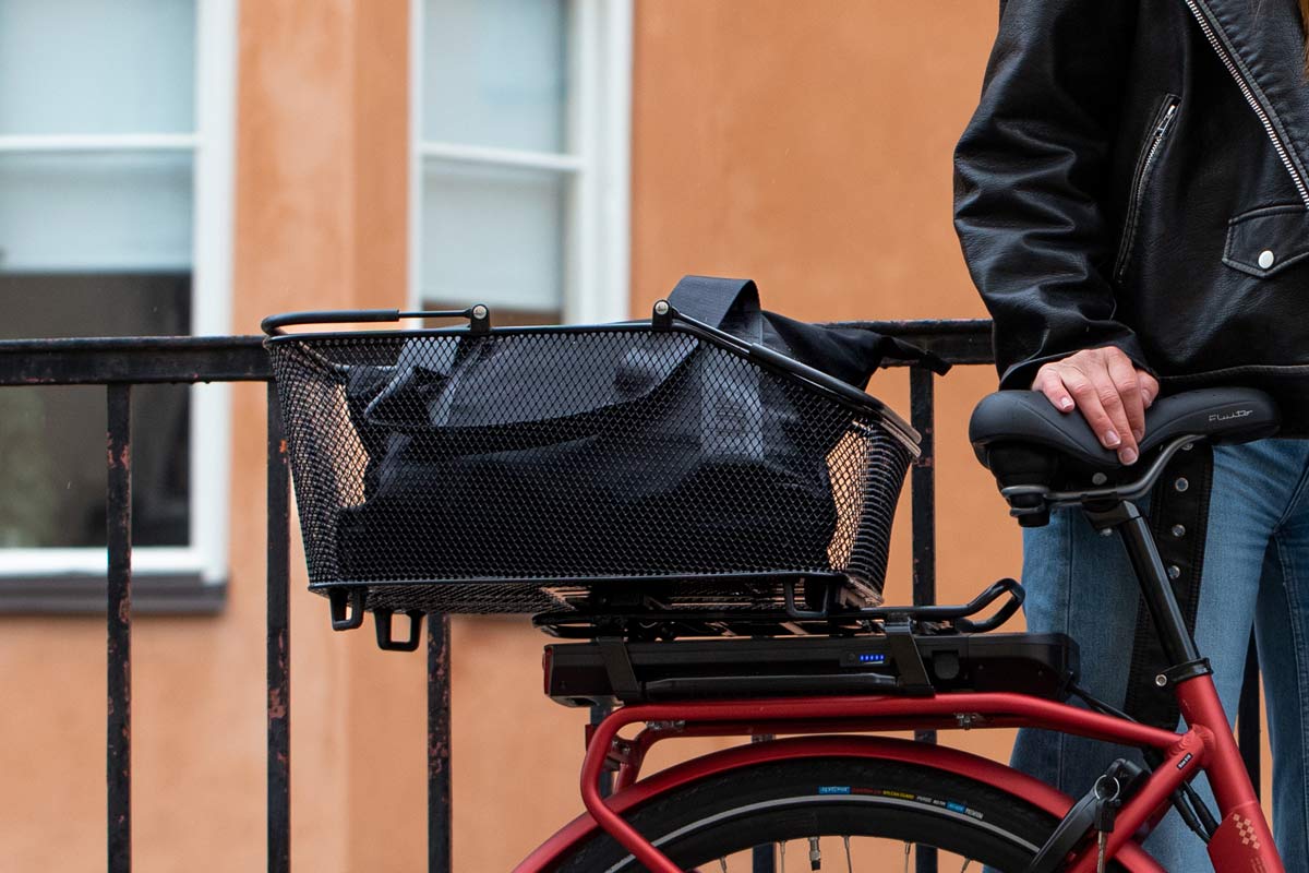 A closeup att a rear big mesh basket on a red bike on the rear carrier.