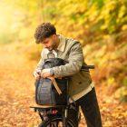 A man in a yellow autumn forest with his bicycle infront of him