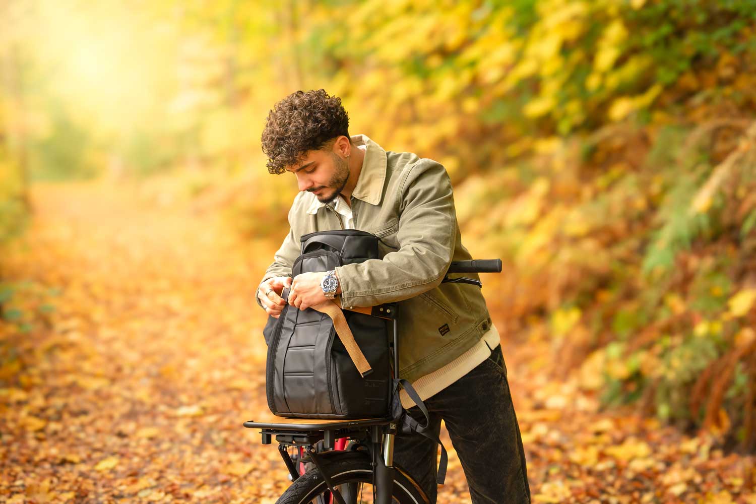 A man in a yellow autumn forest with his bicycle infront of him