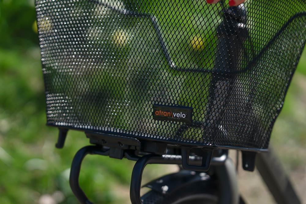 A mesh basket on a front carrier. In the background you can see grass.