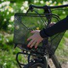 A girl taking off a mesh basket from a front carrier. In the background you can see grass.