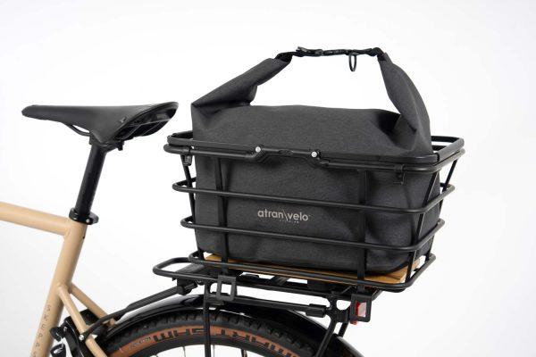 Grey bag with light grey background in studio in a basket on a bike