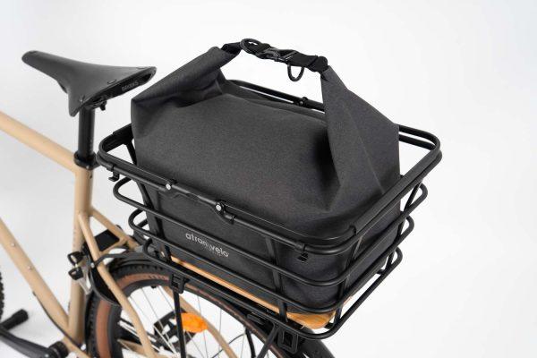 Grey bag with light grey background in studio in a basket on a bike
