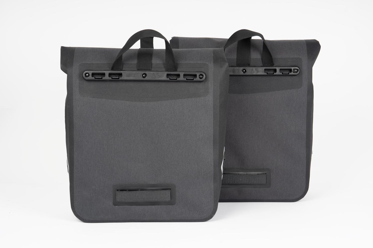 Two dark grey side bags in a studio