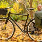 A bicycle with a front top bag and a man is blurred in the background, smiling and looking to the side.