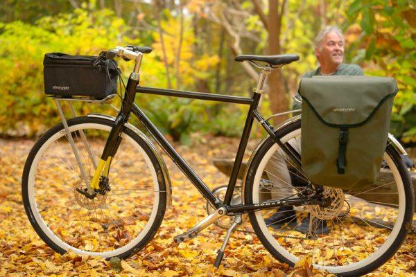 A bicycle with a front top bag and a man is blurred in the background, smiling and looking to the side.