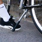 Close-up of a foot lifting up a chrome-colored bike stand.