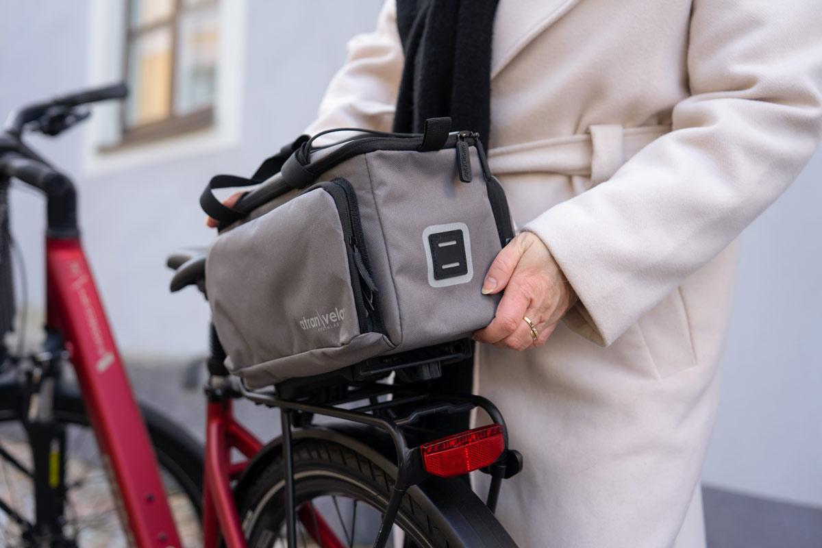 A woman lifting off a grey top bag with the avs system