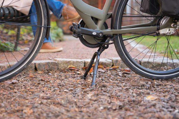 A double kickstand out in nature on abicycle, in the back you can see two feet