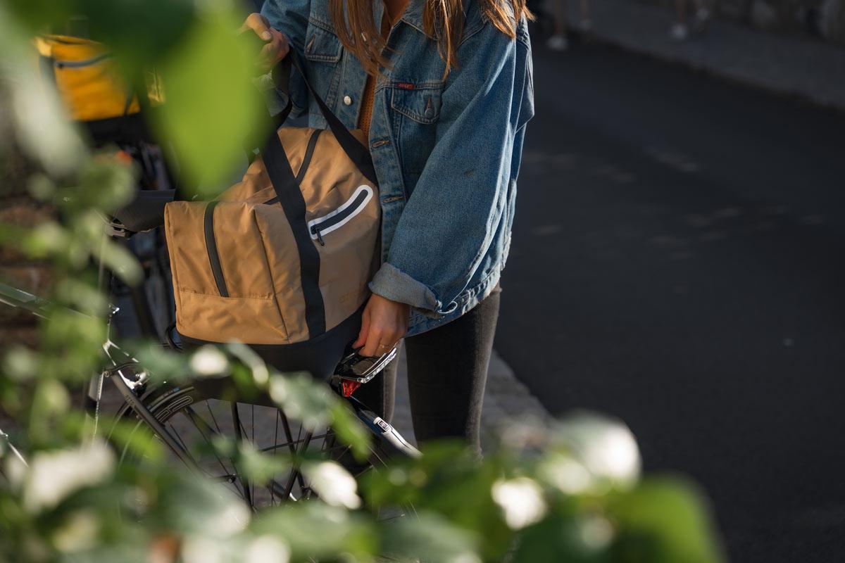 A girl lifting off a brown bag from a rear carrier with the avs system