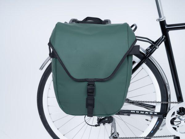 A green sidebag in a studio on a bike