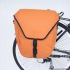 An orange sidebag in a studio on a bike