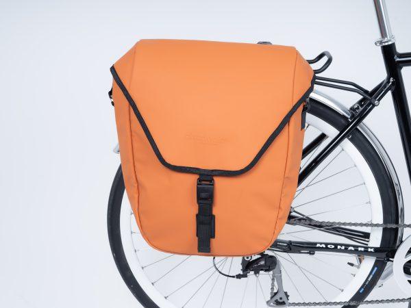 An orange sidebag in a studio on a bike