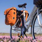 Two orange bags on a bicycle, photographed from below.