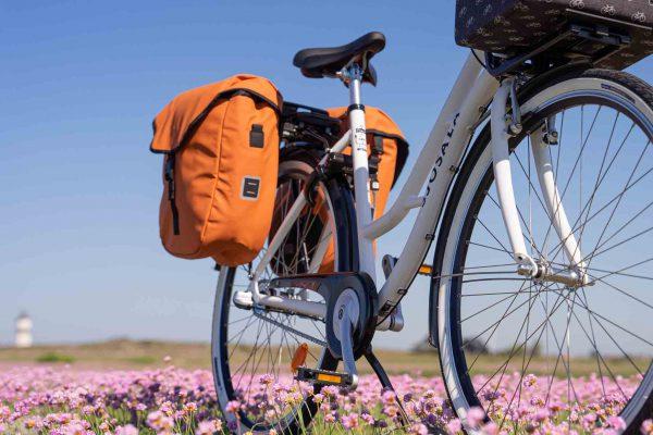 Two orange bags on a bicycle, photographed from below.