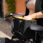 A black top bag with a yellow interior on a bicycle, with a woman's hand rummaging inside the bag.