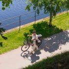 A guy walking with a bicycle that has three gray bags on it.