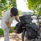 Dark haired gur lifting a sidebag off the bike