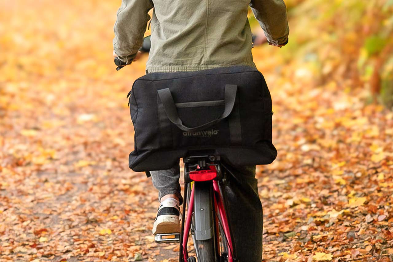 A closeup at a big black top back on a rear carrier, a man is biking.