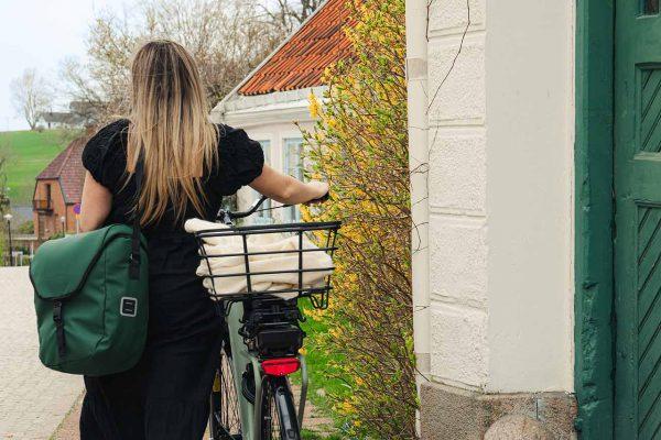 A green bike, green sidebag and a green door and a woman