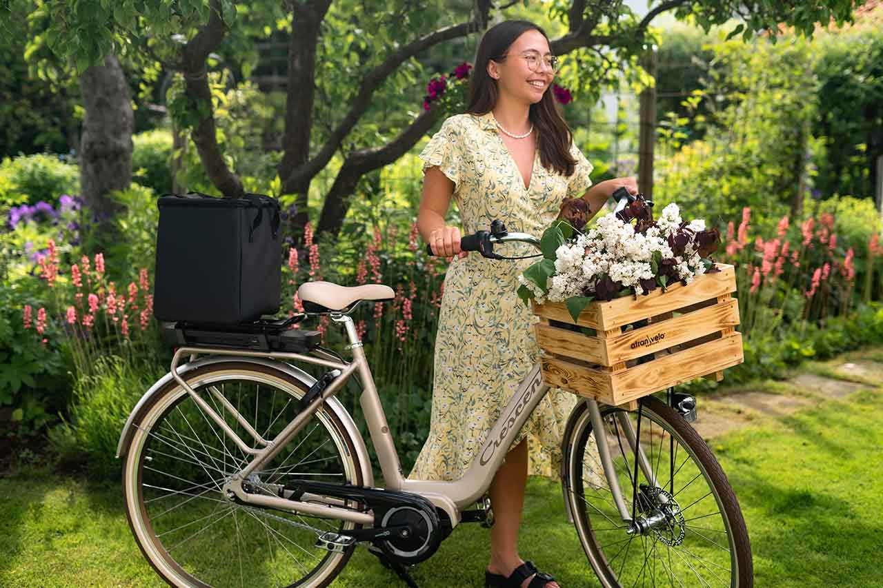 Woman with a bike in a garedn with a wooden basket and a topbag