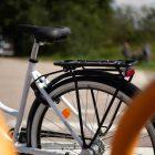 A white bicycle with a black rack at a crosswalk.