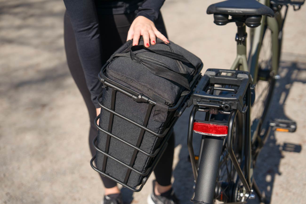 A girl taking off a sidebasket from a rear carrier.