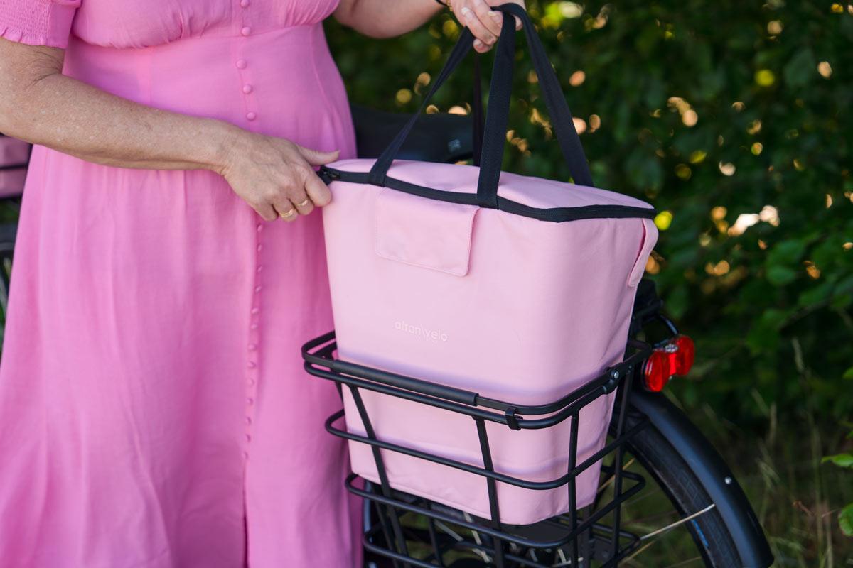 A woman lifting up a pink add 25 from a basket outside
