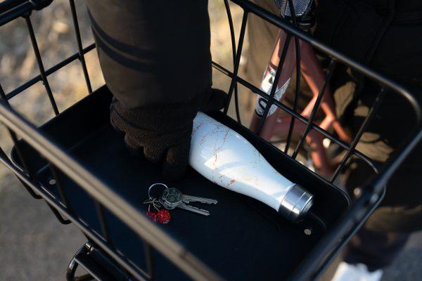 A basket with a plastic bottom and a girl picking up a bottle