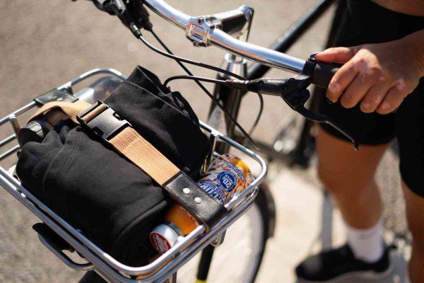 A brown buckleset on a chrome basket at the front of fthe bike.