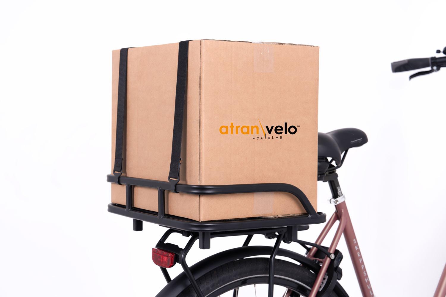 A black crate on a front carrier in a studio with a box on top of it.