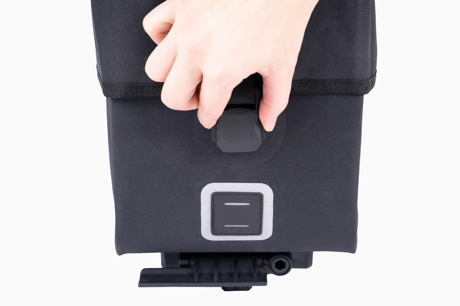 A closeup at a magnetic buckle on a black bag in a studio