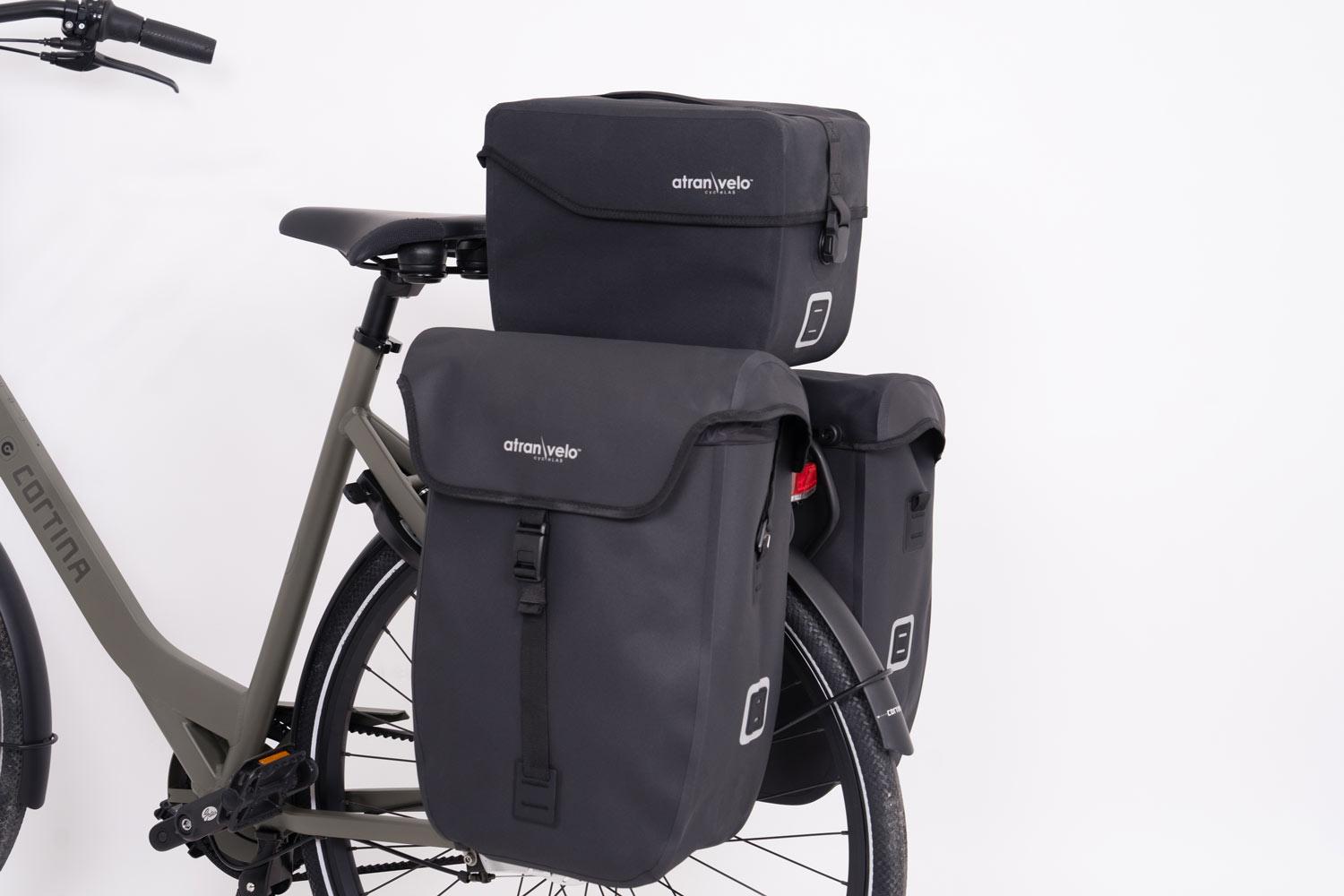 A studiopicture of two sidepanniers and a top bag on a green bicycle