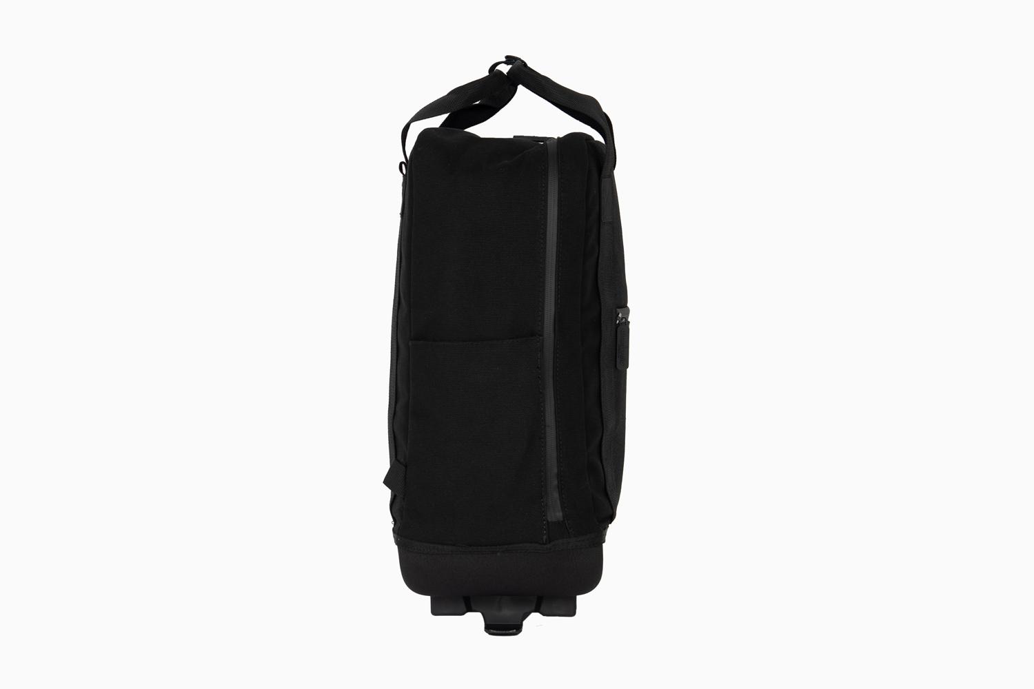 A black thin backpack in a studio from the side
